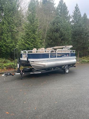 Sun Tracker Bass Buggy 18 DLX 2025 Sun Tracker Bass Buggy 18 DLX pontoon boat on trailer, parked outdoors.