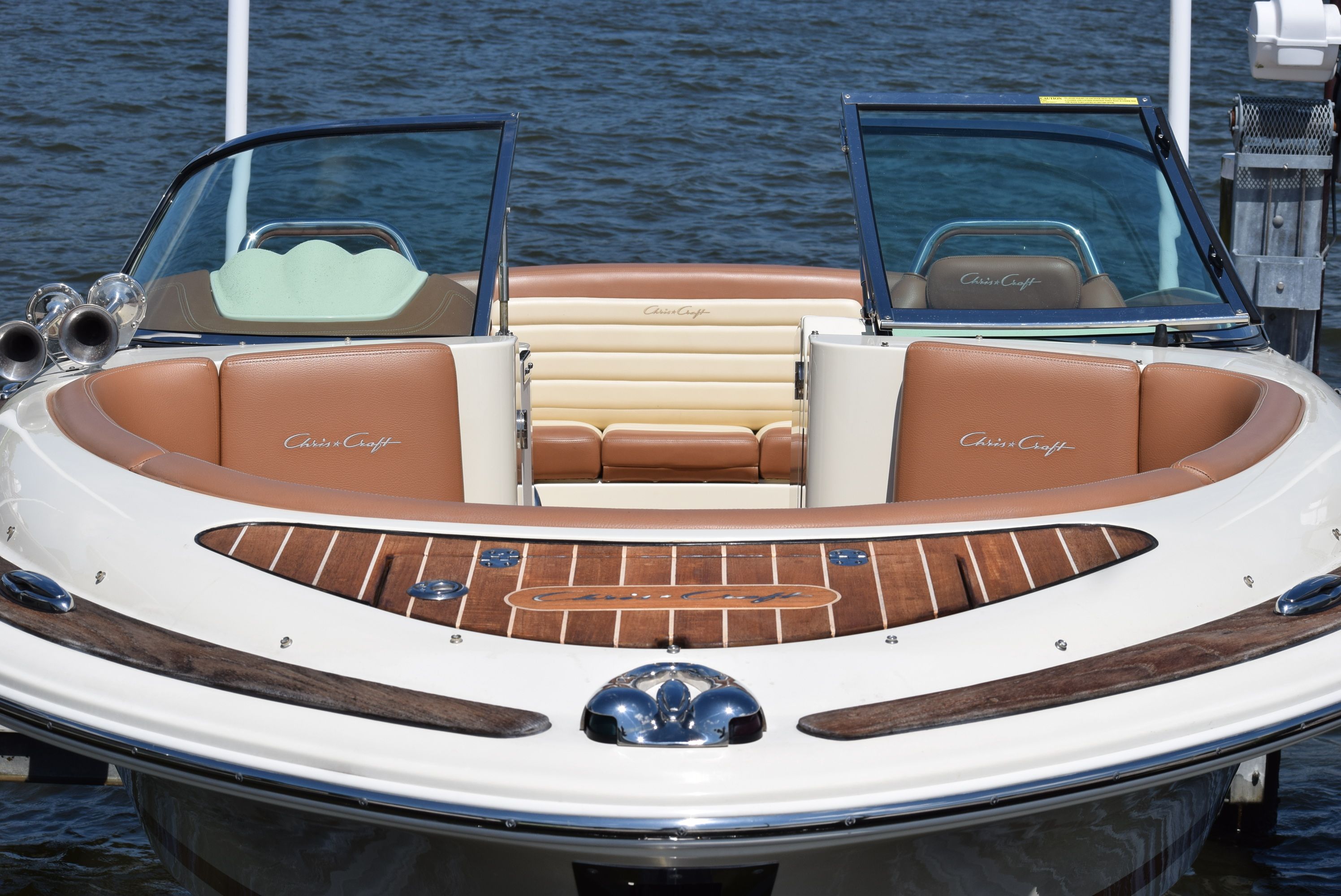 Chris-Craft Launch 25 2014 Chris-Craft Launch 25 boat with elegant seating and wooden deck, docked by the water.