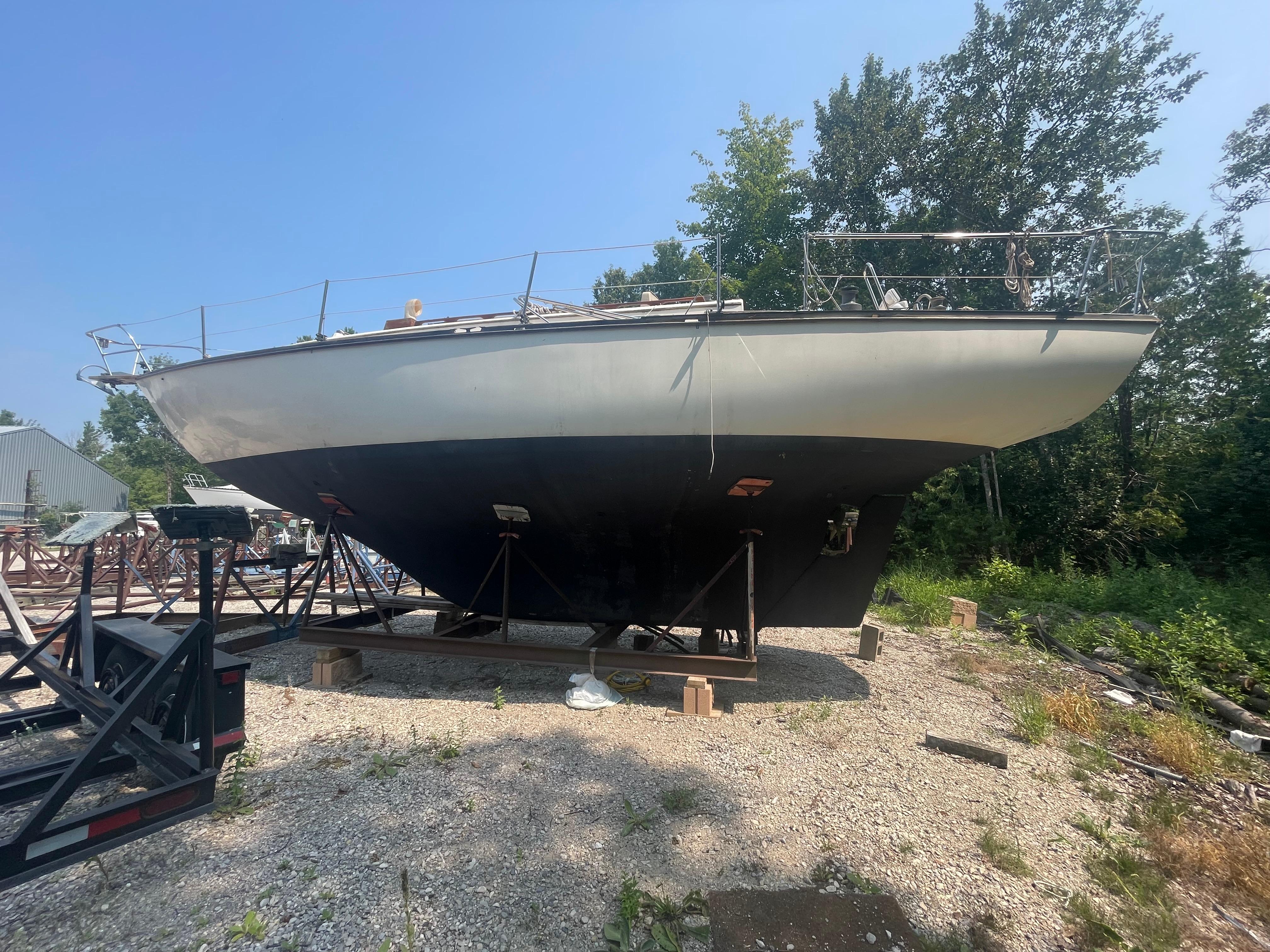 Cape Dory 36 1980 Cape Dory 36 sailboat on dry dock, surrounded by trees and gravel.