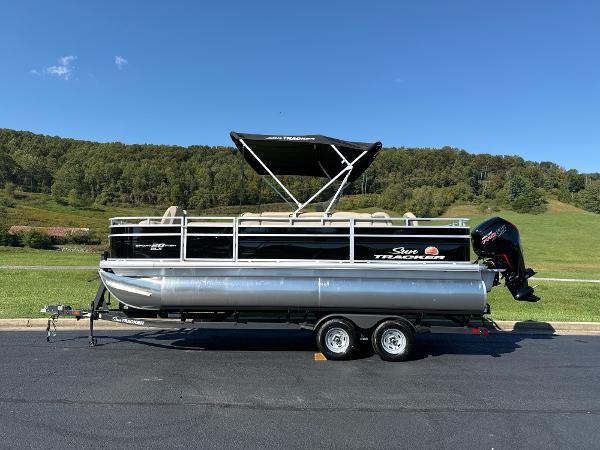 Sun Tracker SportFish 20 DLX 2025 Sun Tracker SportFish 20 DLX pontoon boat on trailer, parked outdoors.