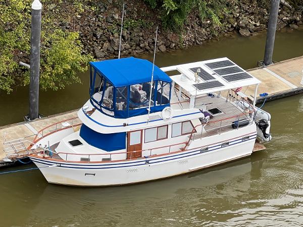 Lindmark 39 Trawler 1983 Lindmark 39 Trawler with blue canopy docked on a river.