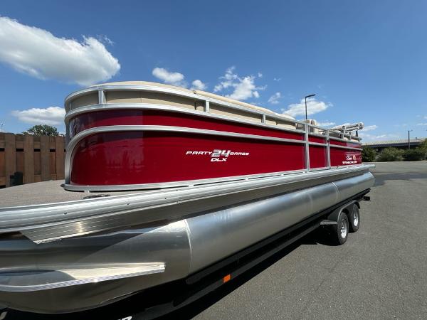 Sun Tracker Party Barge 24 DLX 2025 Sun Tracker Party Barge 24 DLX pontoon boat on trailer, red and silver design.