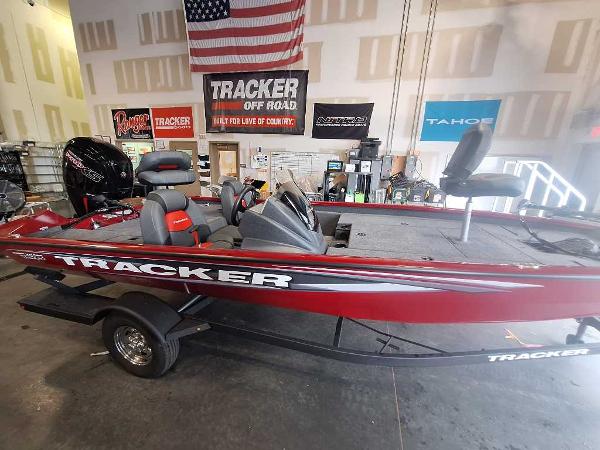 Tracker Pro Team 190 2025 Tracker Pro Team 190 boat in showroom, red exterior, American flag backdrop.