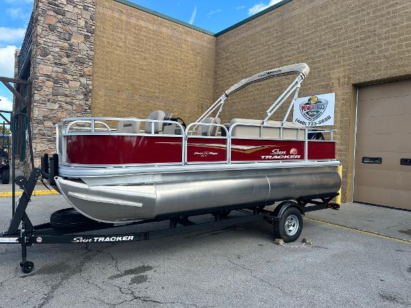 Sun Tracker Bass Buggy 18 DLX 2025 Sun Tracker Bass Buggy 18 DLX pontoon boat on trailer, parked outside a building.