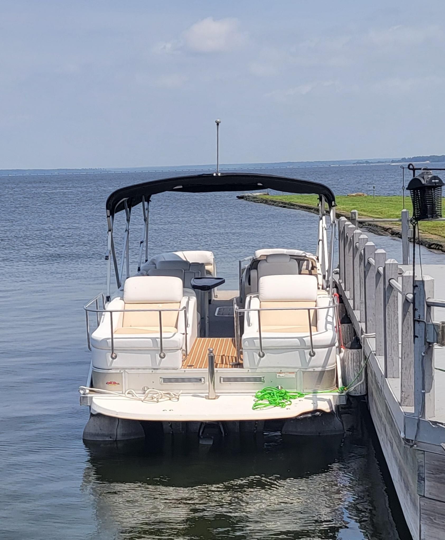 Bennington 2575 QCW 26' 300HP 2012 Bennington 2575 QCW pontoon boat docked by a serene lake.
