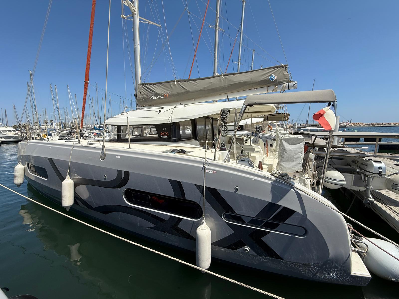 Excess 11 2025 Excess 11 catamaran docked at marina under clear blue sky.