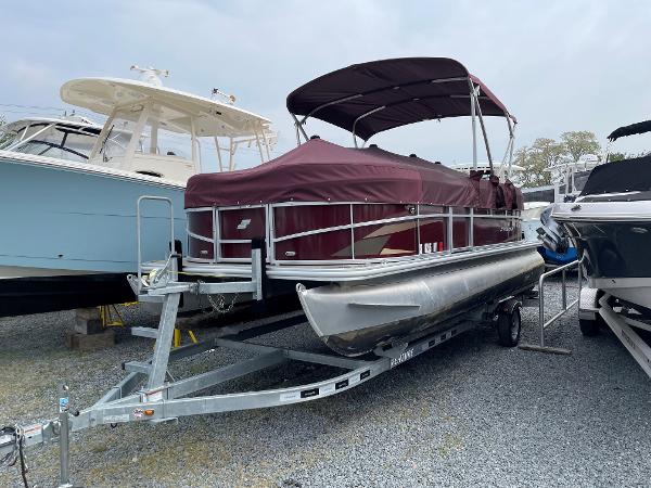 Starcraft LX20R 2022 Starcraft LX20R pontoon boat with maroon cover on trailer, parked in a marina.