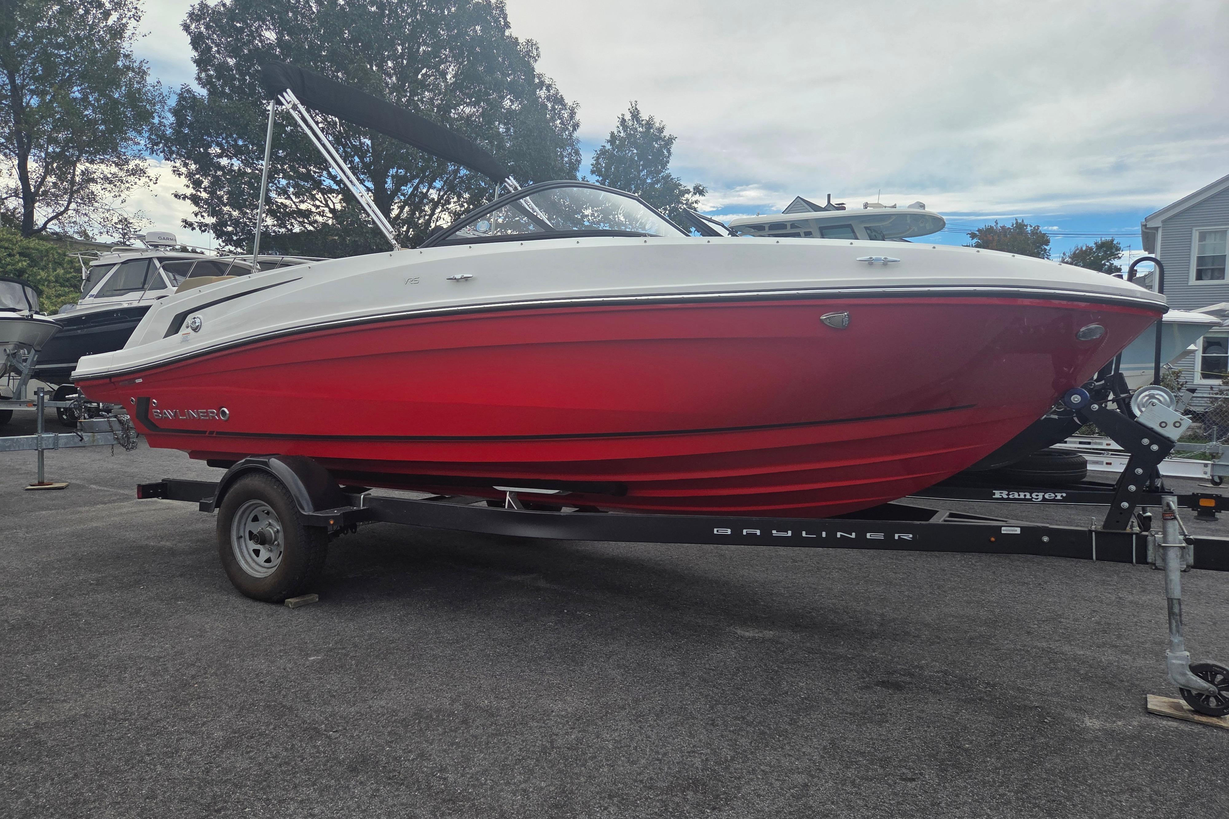 Bayliner VR5 Bowrider I/O 2024 Bayliner VR5 Bowrider I/O with red hull on trailer, parked outdoors.