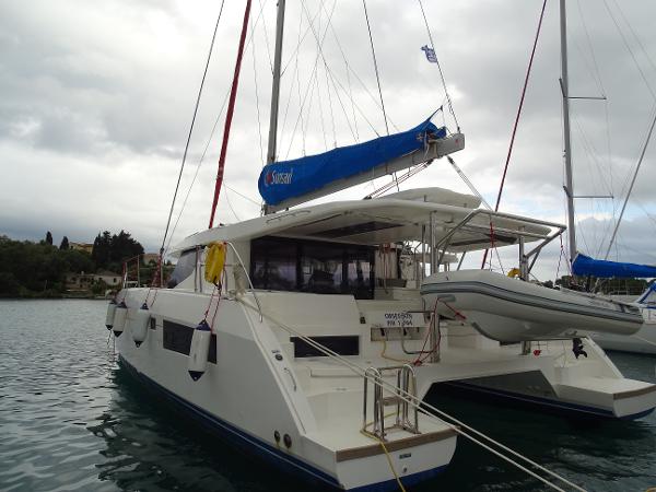 Leopard 45 2017 Leopard 45 catamaran with blue sail, docked in calm waters.