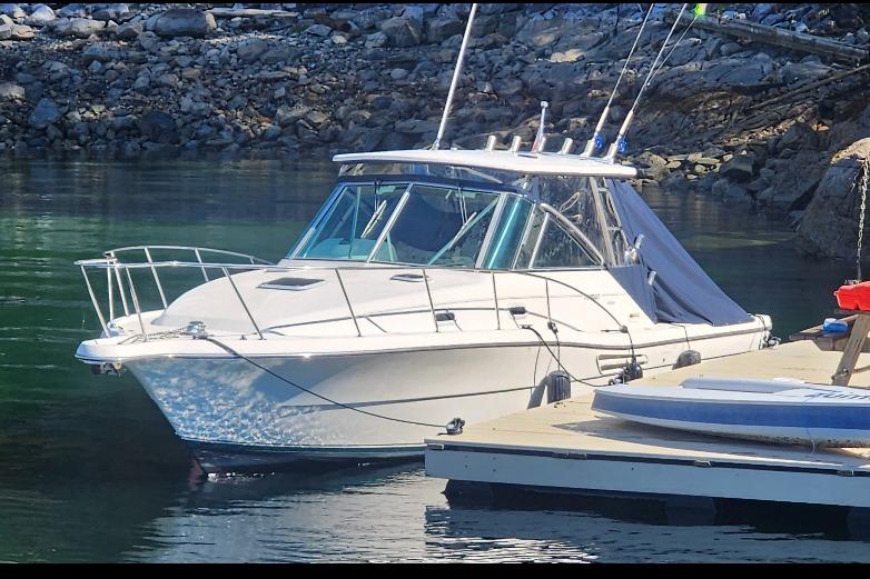 Pursuit 3000 Express 2000 Pursuit 3000 Express boat docked in a serene rocky cove.