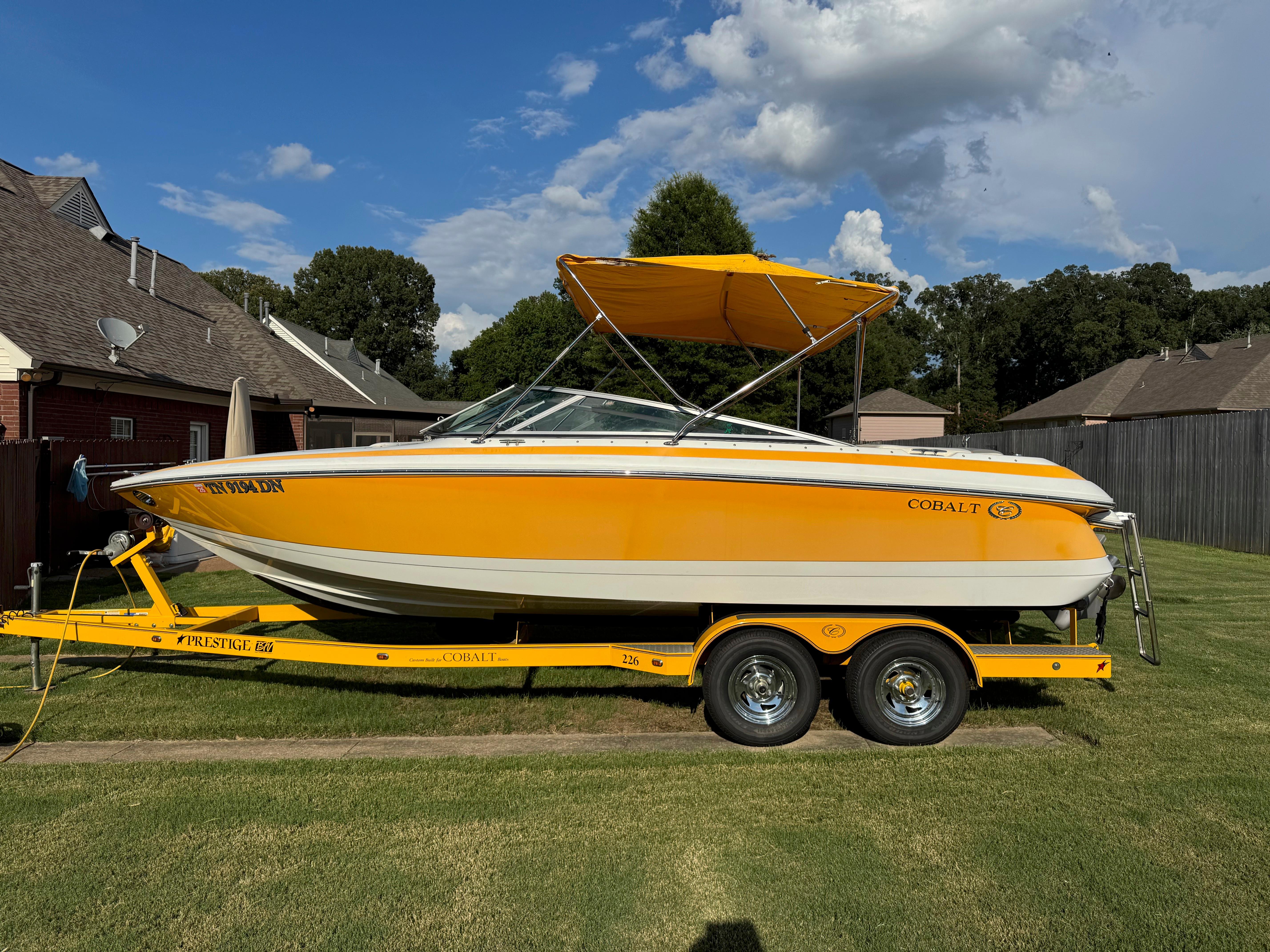Cobalt 226 2006 Cobalt 226 boat with yellow canopy on trailer, parked on grass.
