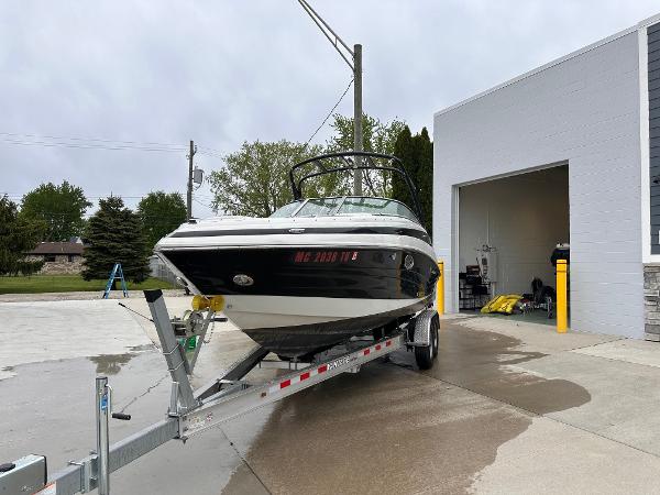 Crownline 255 SS 2014 Crownline 255 SS boat on a trailer outside a garage.
