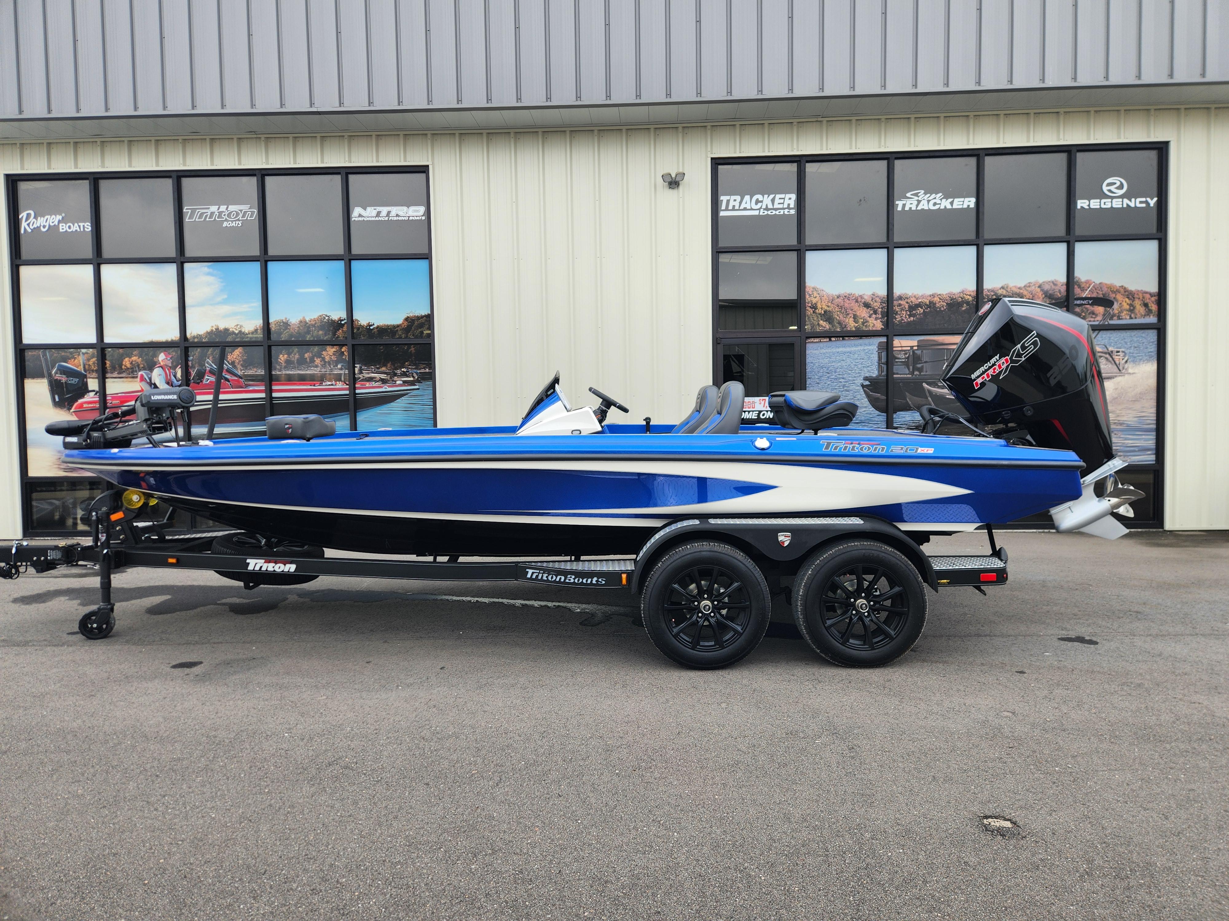 Triton 20XP Patriot 2025 Triton 20XP Patriot boat on trailer, parked outside a showroom.