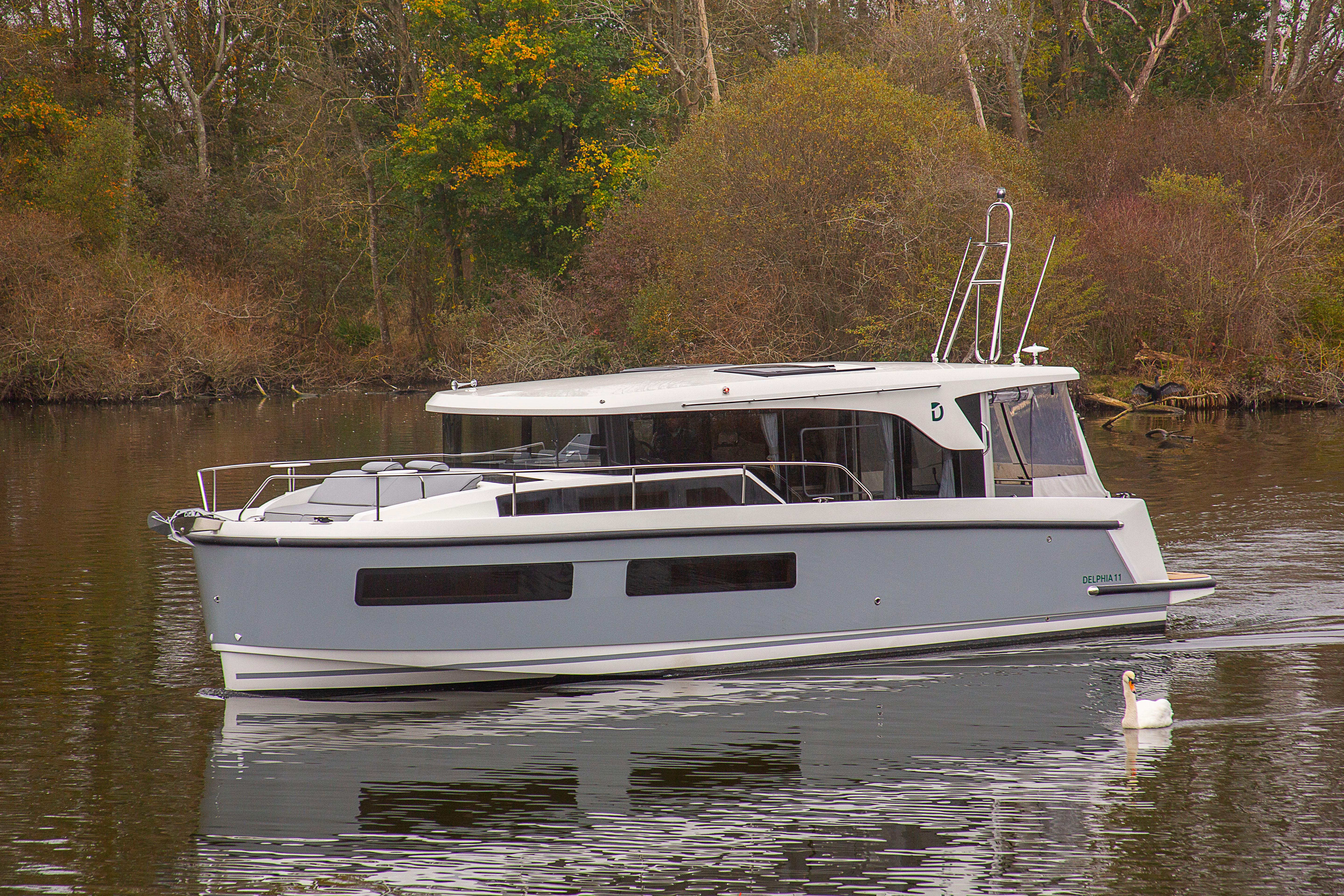 Delphia 11 Sedan 2026 Delphia 11 Sedan cruising on a serene lake with lush greenery.