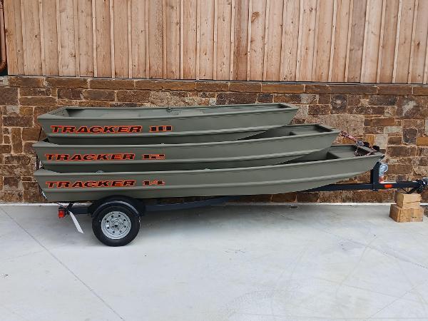 Tracker Grizzly 12 Jon 2025 Tracker Grizzly 12 Jon boats stacked on a trailer against a brick wall.