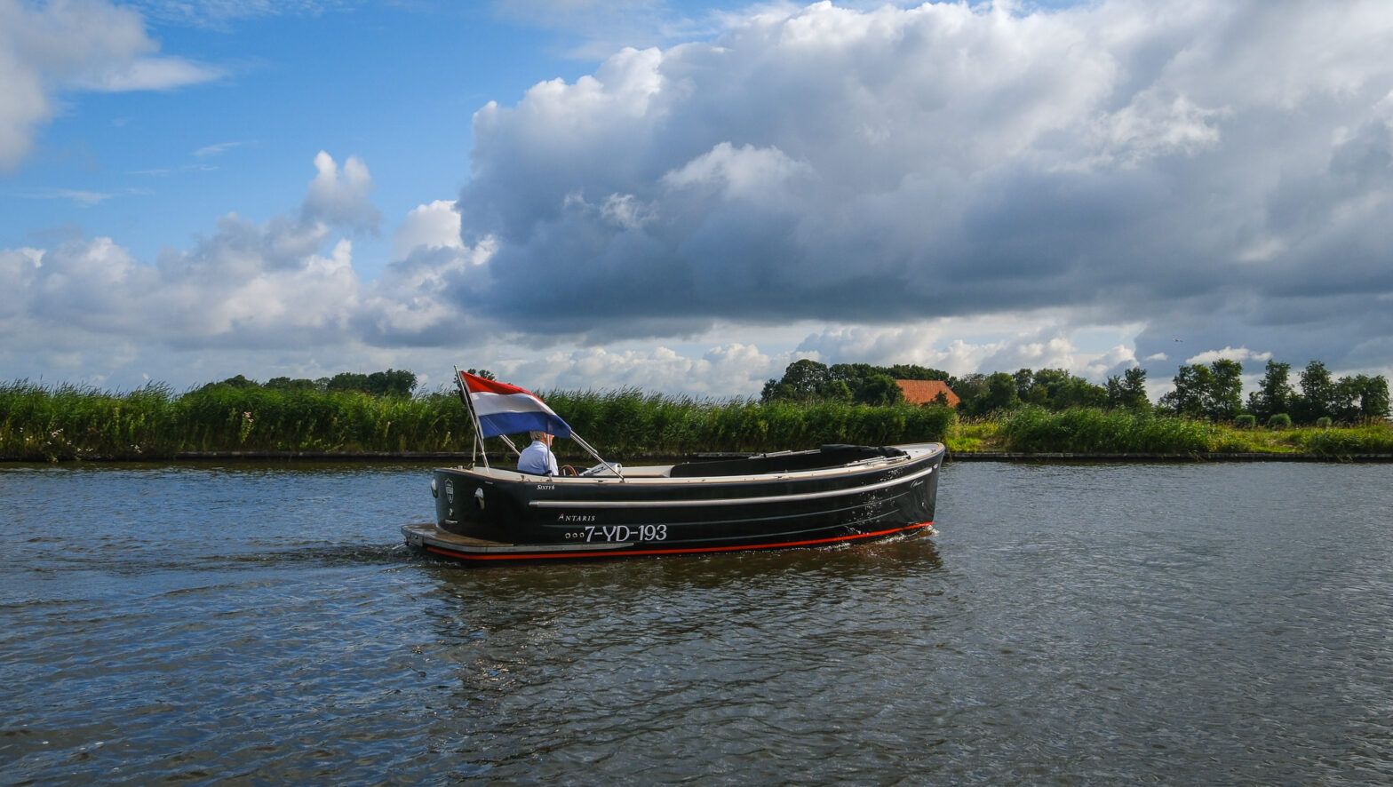 Antaris Sixty6 – 52 pk 2020 Antaris Sixty6 boat cruising on a scenic river under a cloudy sky.