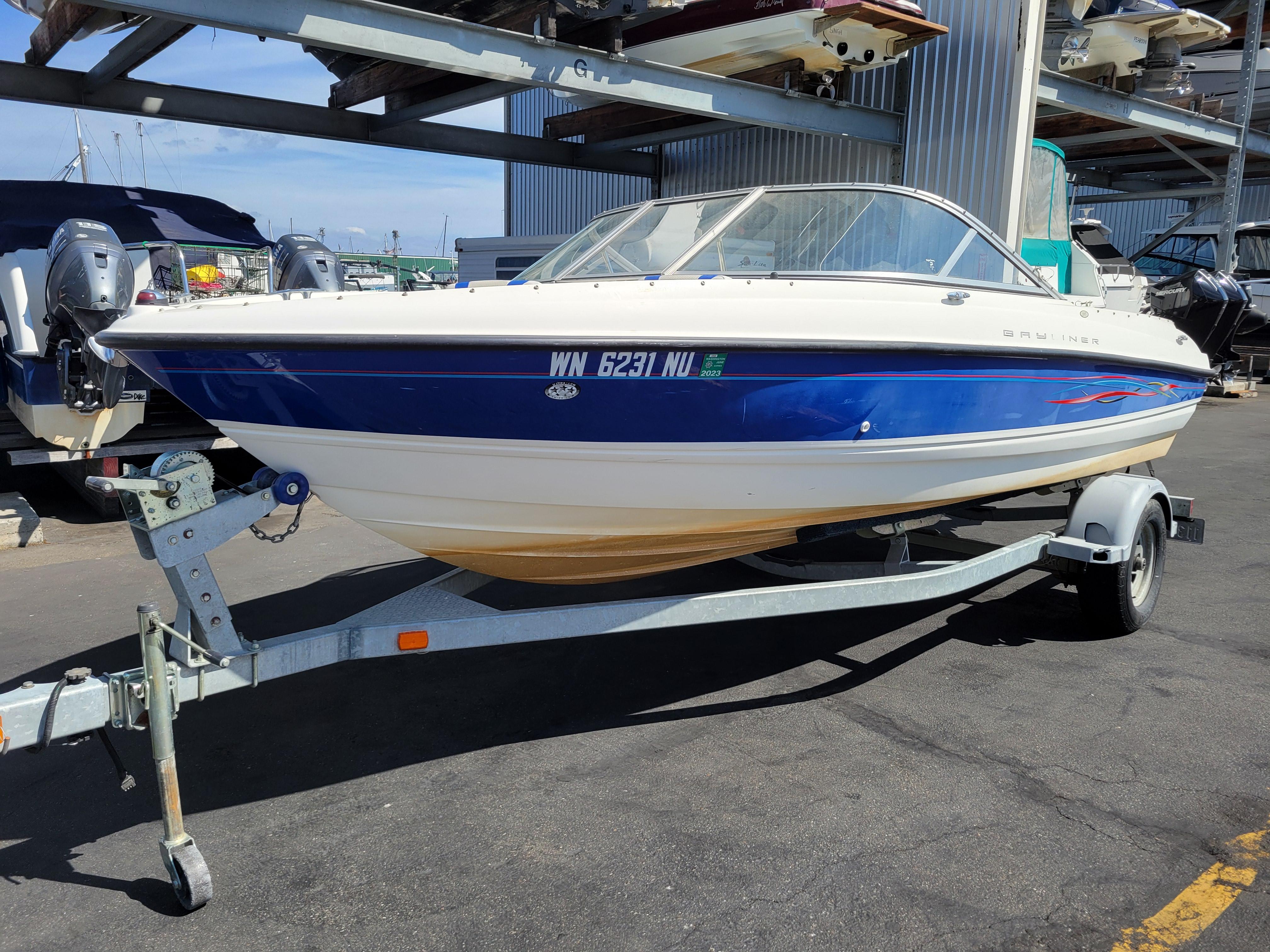 Bayliner 195 2006 Bayliner 195 boat on trailer, blue and white design, parked in marina.