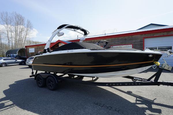 Four Winns H2 Surf 2023 Four Winns H2 Surf boat on trailer, black hull, outdoor dealership.