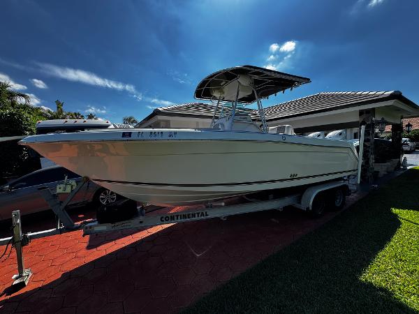 Robalo R260 Center Console 2004 Robalo R 260 boat on trailer, parked in driveway under clear blue sky.