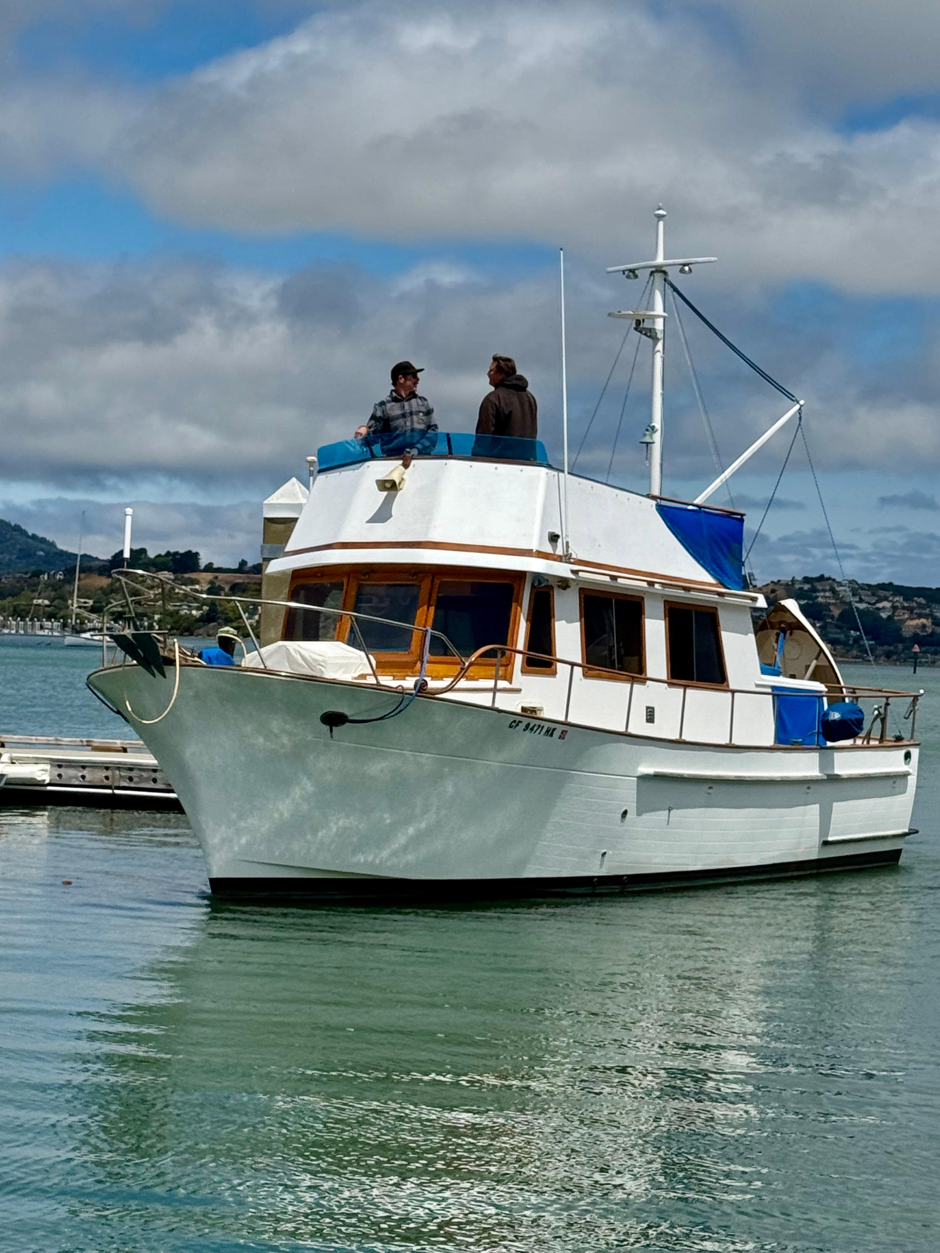 CHB 34 Tri Cabin 1981 CHB 34 Tri Cabin boat docked with two people on deck, under cloudy sky.