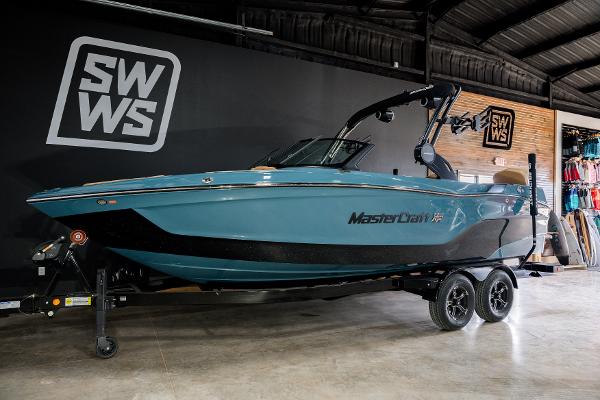 MasterCraft XT23 2025 MasterCraft XT23 boat in showroom, blue and black design, on trailer.