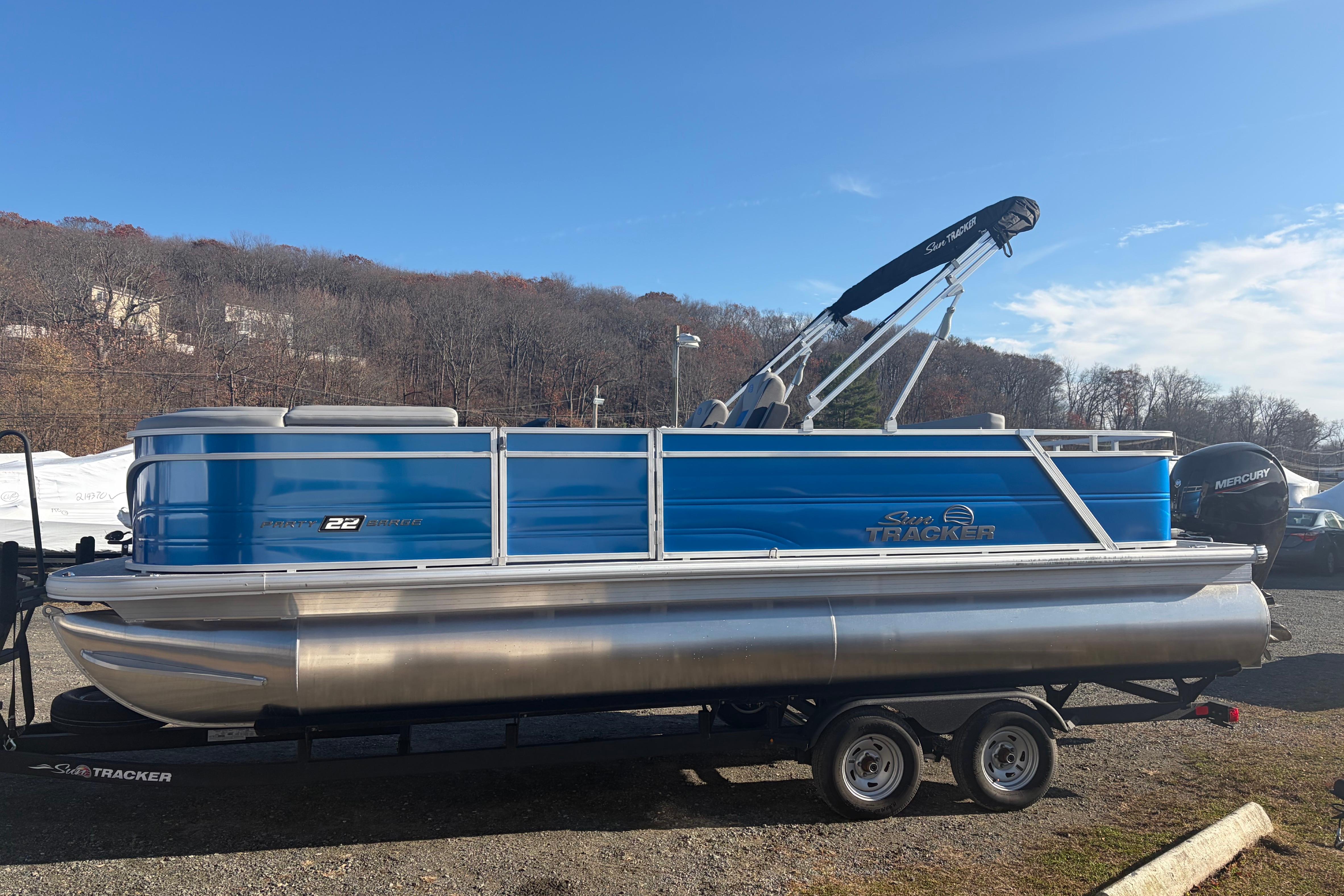 Sun Tracker Party Barge 22 RF DLX 2026 Sun Tracker Party Barge 22 RF DLX pontoon boat on trailer, blue exterior.