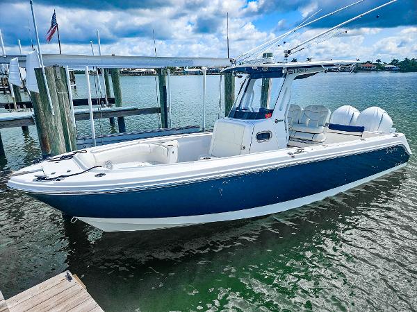 Edgewater 262CC 2023 Edgewater 262CC boat docked, featuring sleek design and dual engines, under a partly cloudy sky.