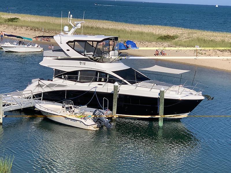 Sea Ray Fly 520 2018 Sea Ray Fly 520 yacht docked by a sandy beach with clear blue water.