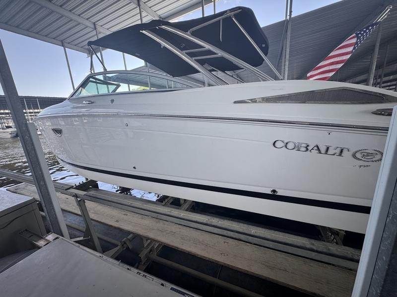 Cobalt 302 2009 Cobalt 302 boat docked under a covered marina with American flag.