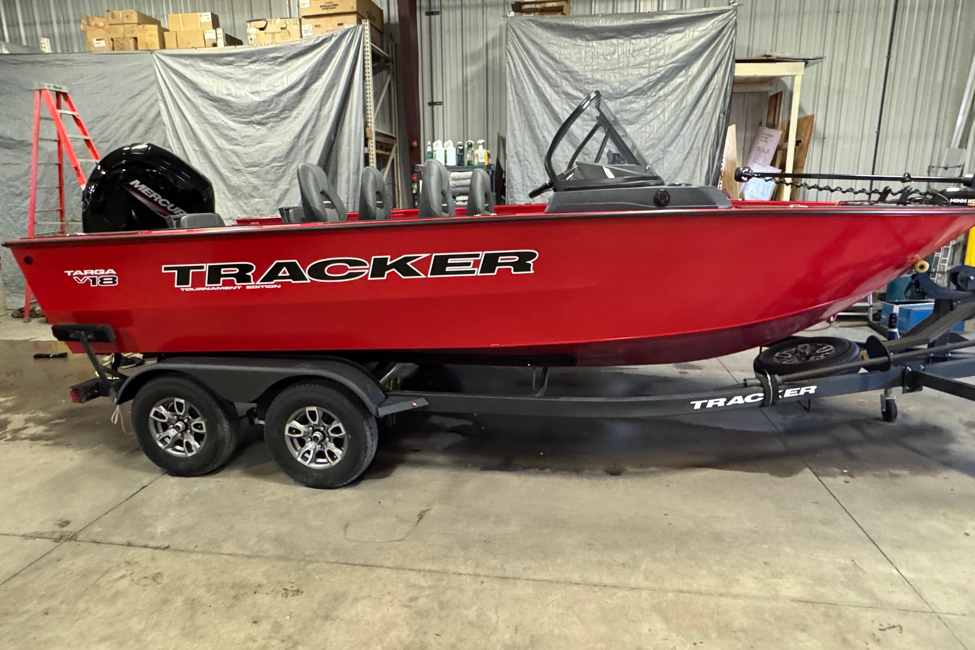 Tracker Targa V-18 Combo 2026 Tracker Targa V-18 Combo boat in a garage, vibrant red color, on a trailer.