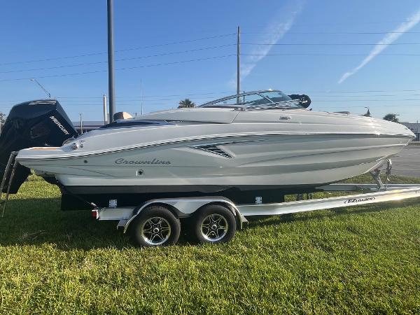 Crownline 260 XSS 2022 Crownline 260 XSS boat on trailer, parked on grass under clear blue sky.