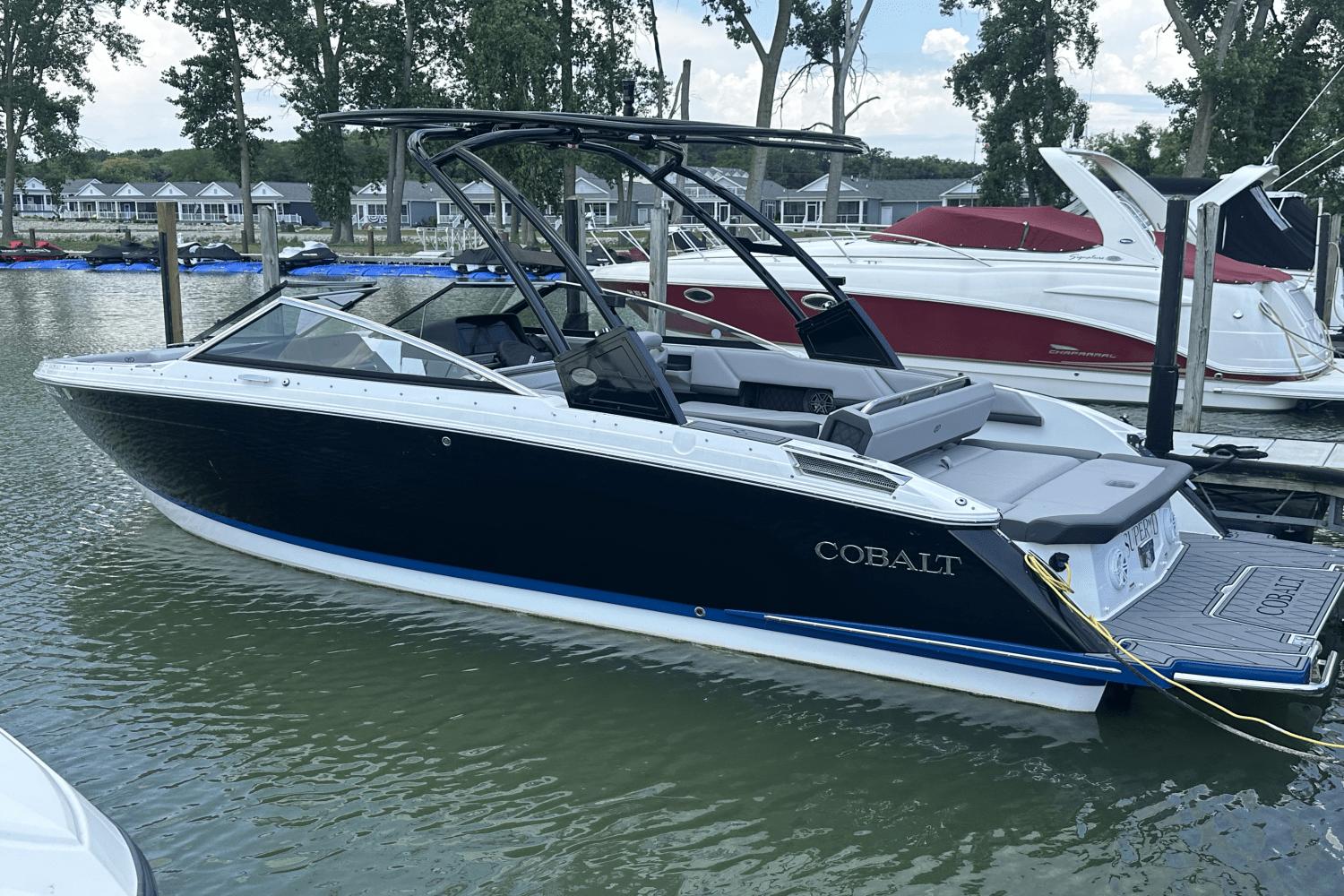 Cobalt R6 2021 Cobalt R6 boat docked on a calm lake, surrounded by trees and other boats.