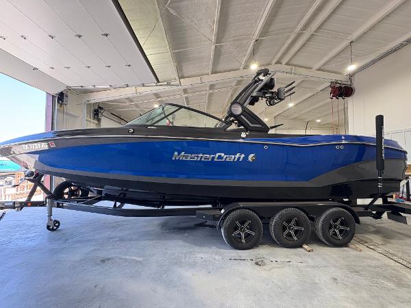 MasterCraft X26 2022 MasterCraft X26 boat in a garage, blue exterior, on a trailer.