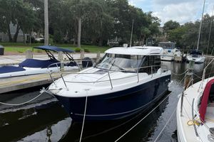 Jeanneau NC 895 2020 Jeanneau NC 895 boat docked in a marina, surrounded by trees and other boats.