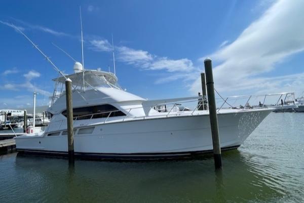 Hatteras 55 Convertible 2002 Hatteras 55 Convertible yacht docked in marina under clear blue sky.