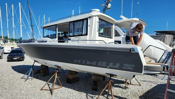 Nimbus C9 2024 Nimbus C9 #137 boat on stands at marina, person inspecting.