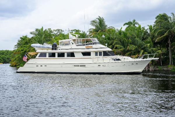 Hatteras 78 CMY 1991 Hatteras 78 CMY yacht cruising on a tropical river with lush greenery.