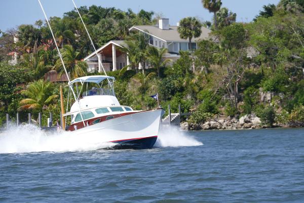 Rybovich Sport Fish 1949 Rybovich Sport Fish boat cruising near a lush shoreline.