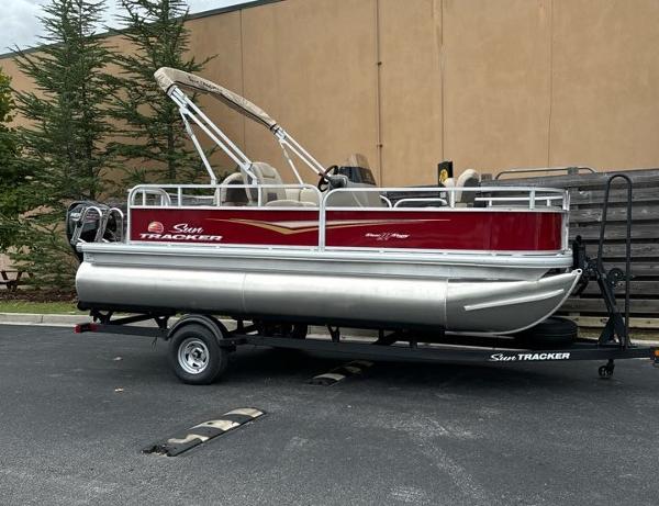 Sun Tracker Bass Buggy 18 DLX 2025 Sun Tracker Bass Buggy 18 DLX pontoon boat on trailer, parked outdoors.