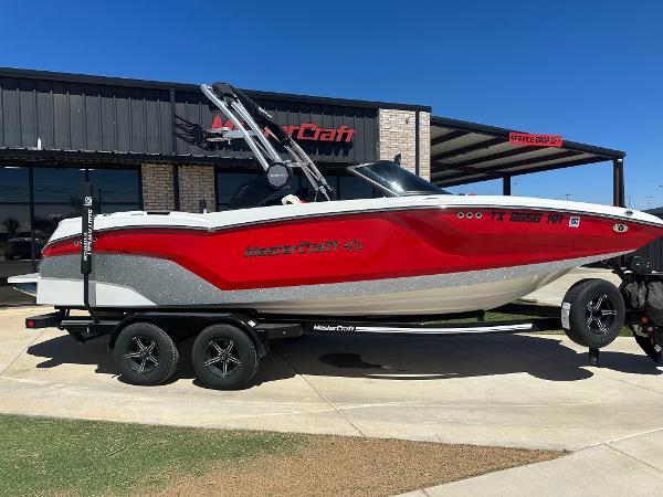 MasterCraft NXT22 2023 MasterCraft NXT22 boat in red and white on a trailer outside a dealership.