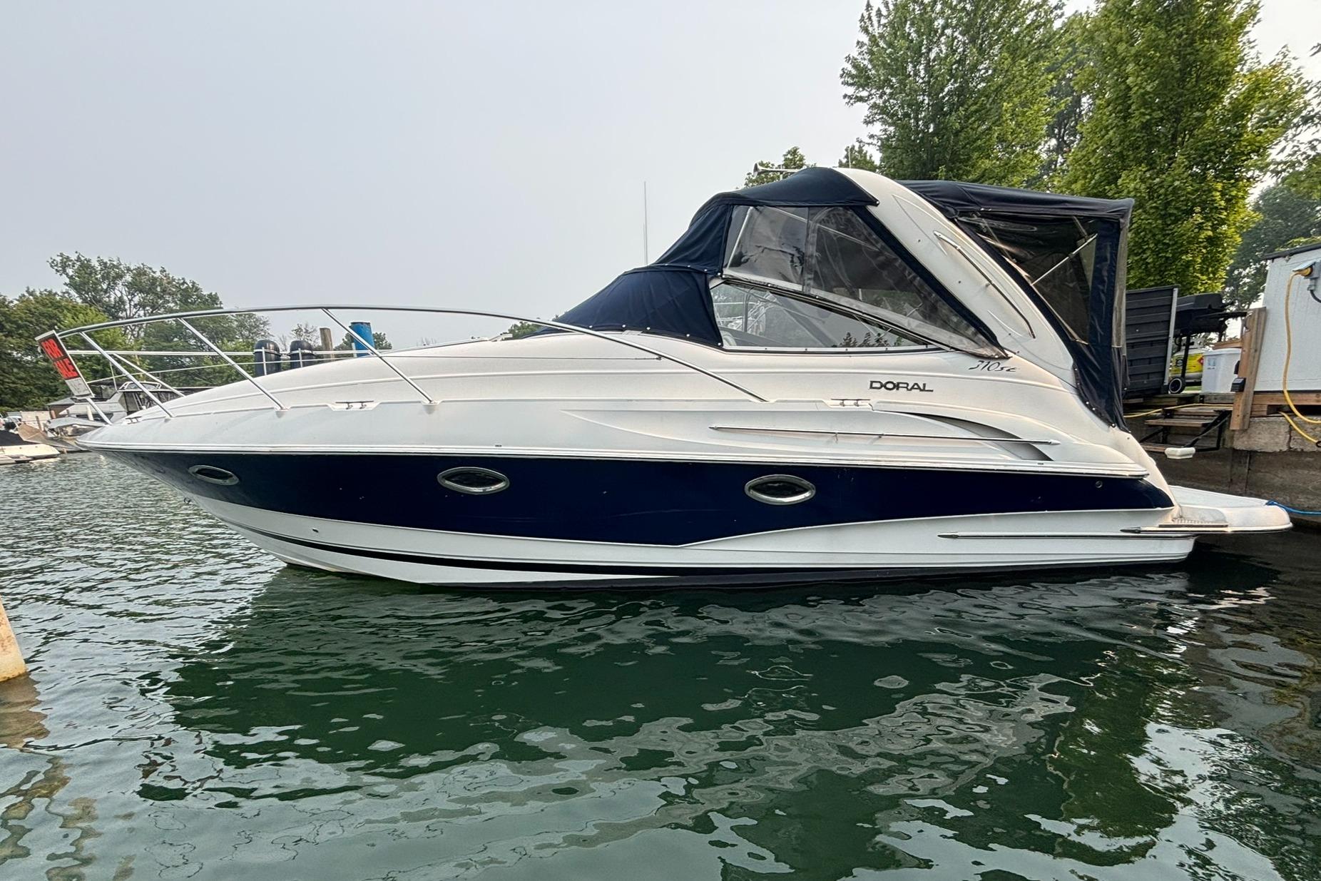 Doral 310 SE 2002 Doral 310 SE boat docked on calm water, featuring sleek design and blue accents.