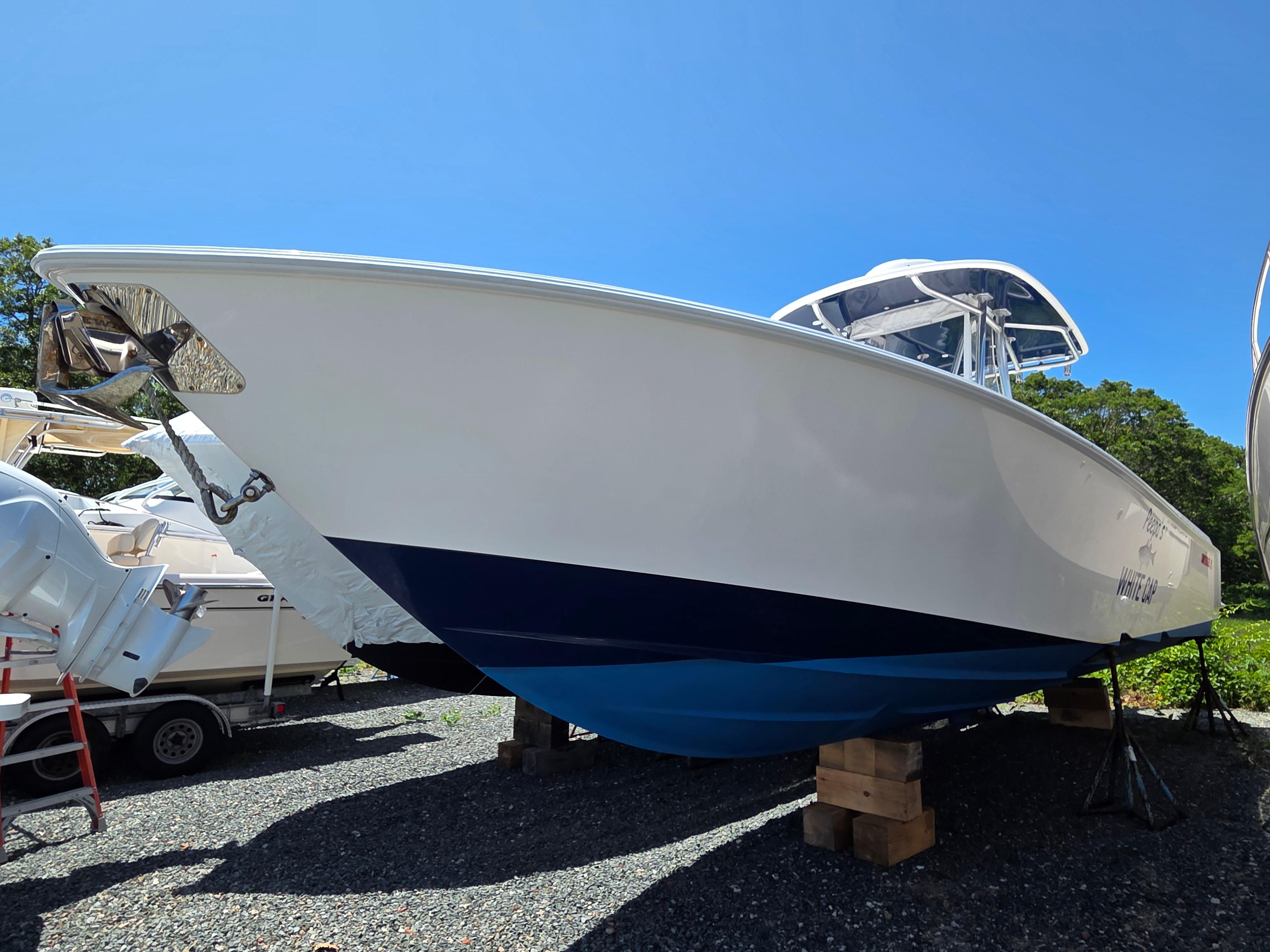 Contender 32 ST 2016 Contender 32 ST boat on blocks, blue and white hull, sunny day.