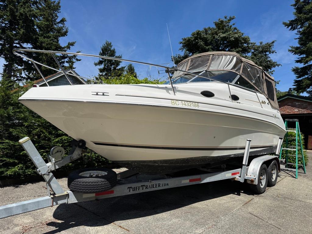 Sea Ray 240 Sundancer 1997 Sea Ray 240 Sundancer boat on trailer, surrounded by trees, under clear blue sky.