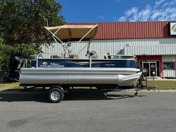 Sun Tracker Bass Buggy 18 DLX 2025 Sun Tracker Bass Buggy 18 DLX pontoon boat on trailer, parked outdoors.