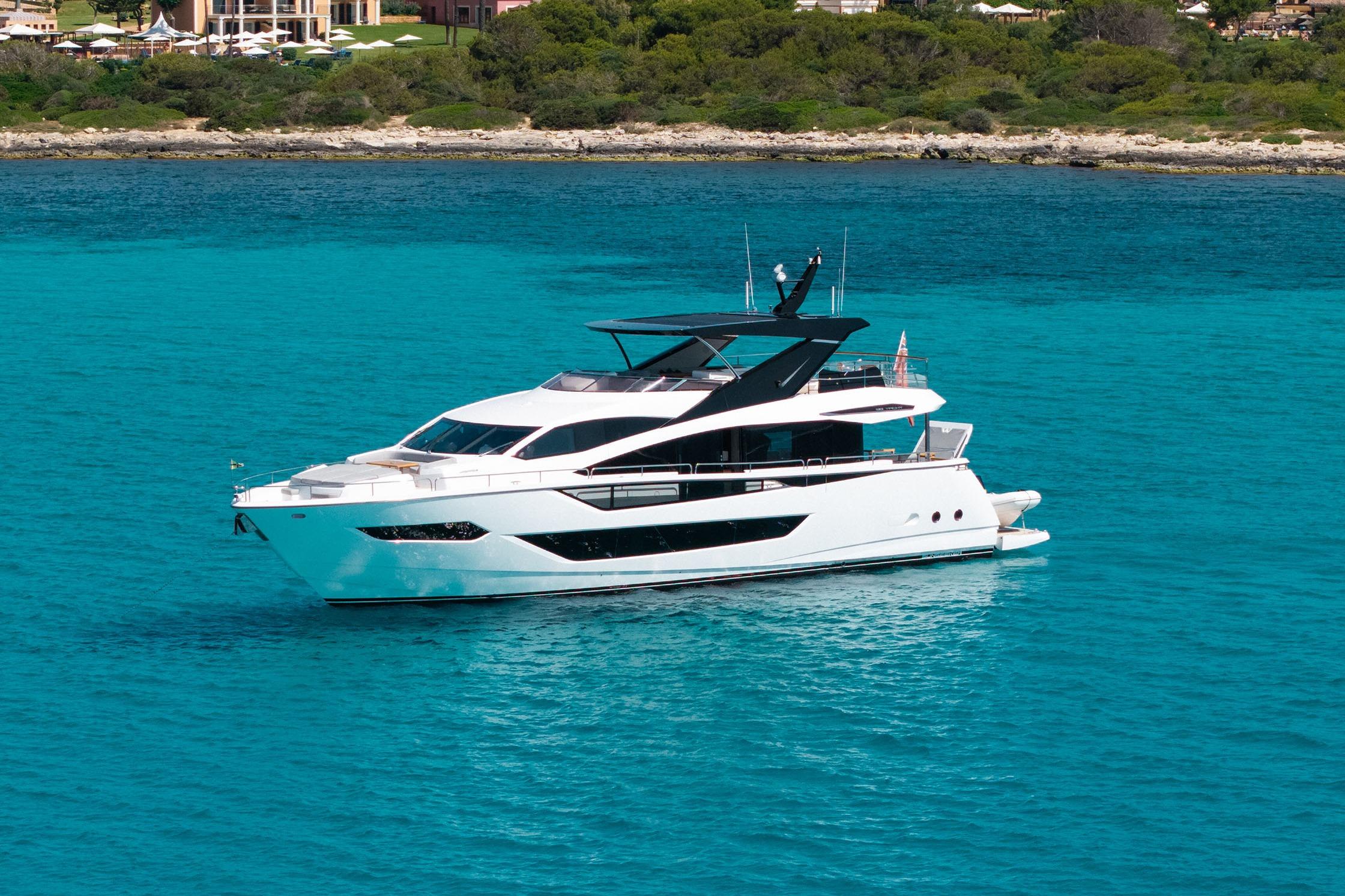 Sunseeker 88 Yacht 2022 Sunseeker 88 Yacht on turquoise water near a lush coastline.