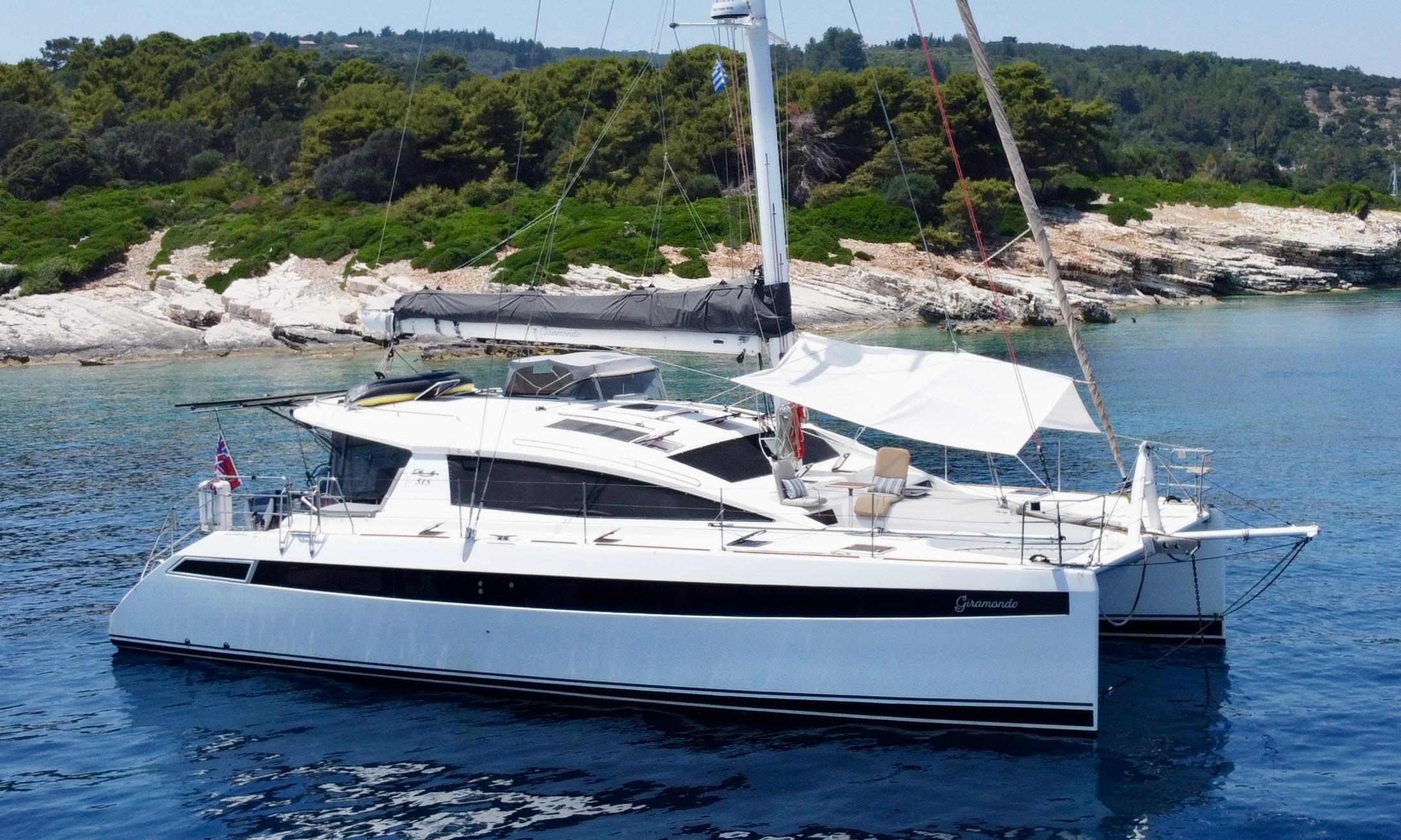 Privilege 515 Luxury Privilege 515 catamaran sailing near a scenic rocky coastline, 2010 model.