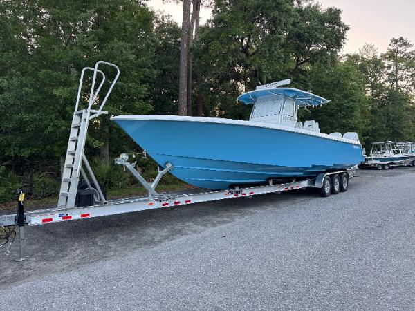 Contender 39ST 2025 Contender 39ST boat on trailer, parked on road, surrounded by trees.