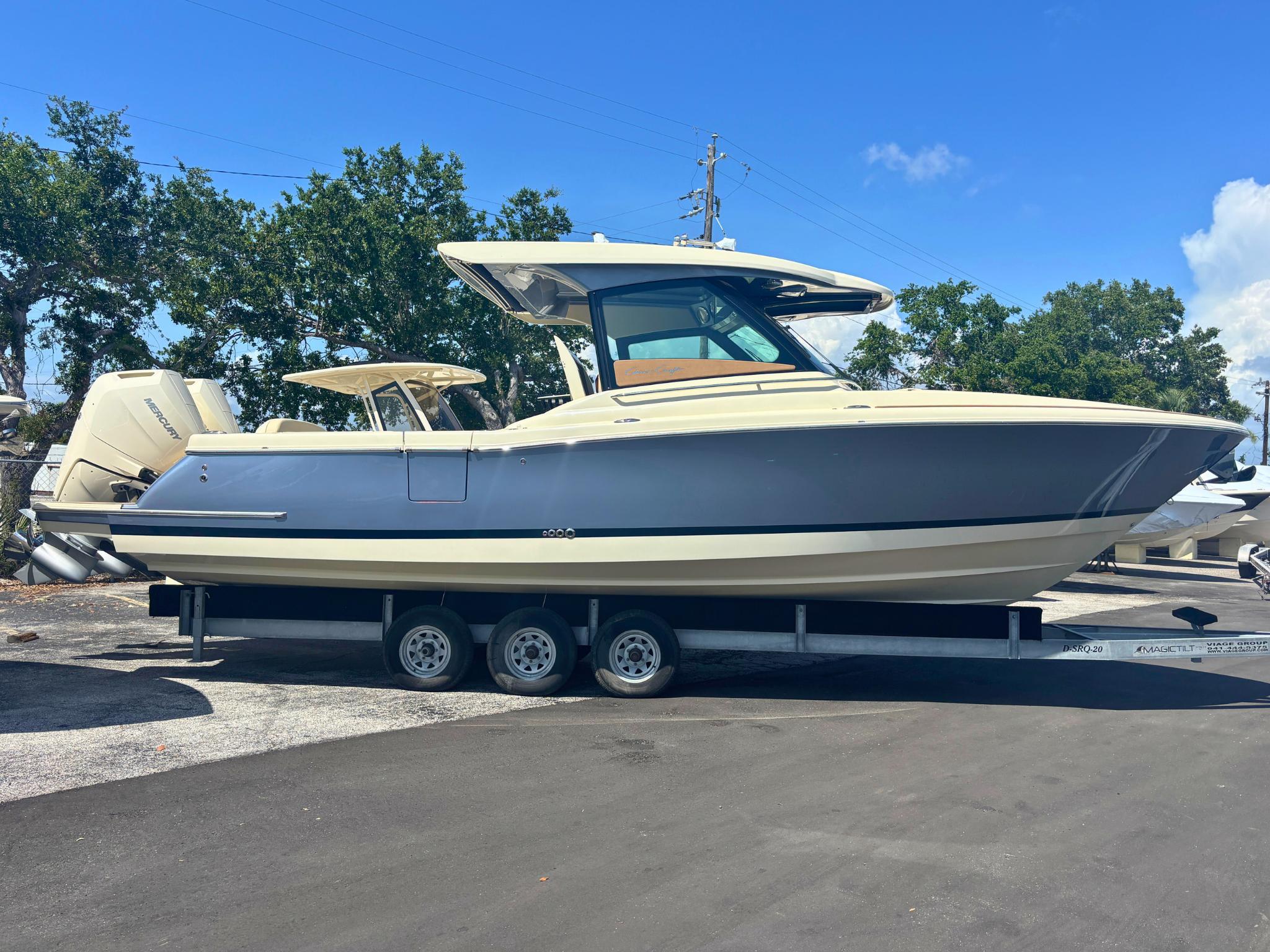 Chris-Craft Calypso 32 2025 Chris-Craft Calypso 32 boat on trailer, parked outdoors under clear blue sky.