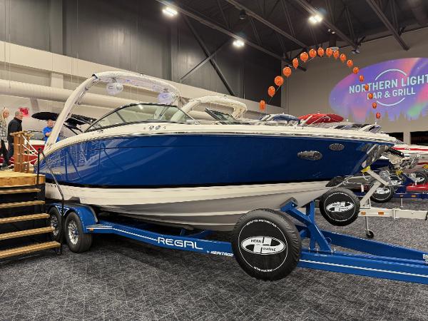 Regal LS6 2025 Regal LS6 boat on display with blue hull and trailer at indoor event.