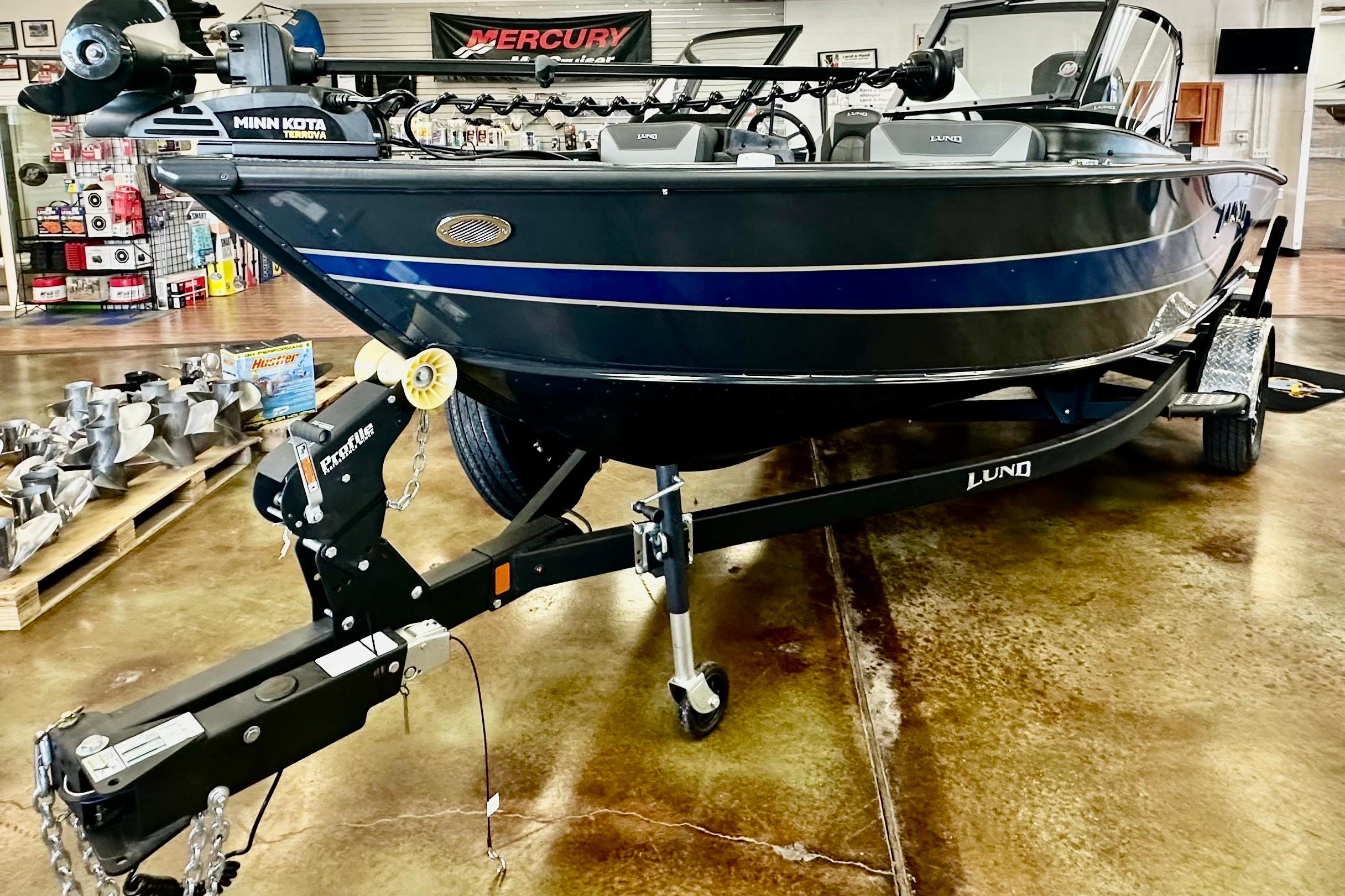 Lund 1875 Crossover XS 2026 Lund 1875 Crossover XS boat on trailer in showroom, featuring Minn Kota Terrova motor.